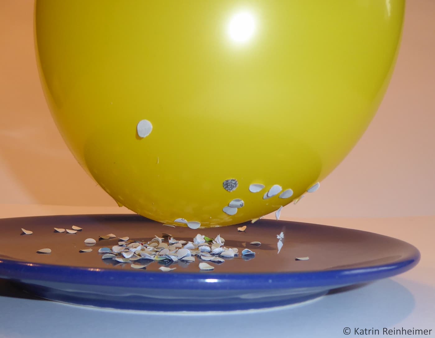 Papierschnipsel werden von einem elektrostatisch aufgeladenen Luftballon angezogen.