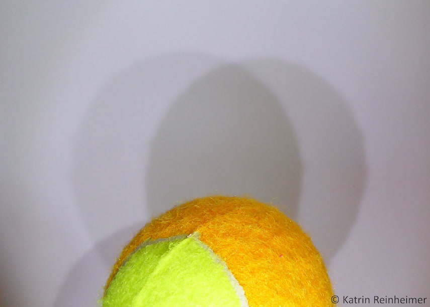 Halbschatten und Kernschatten eines Tennisballs mit zwei Taschenlampen.