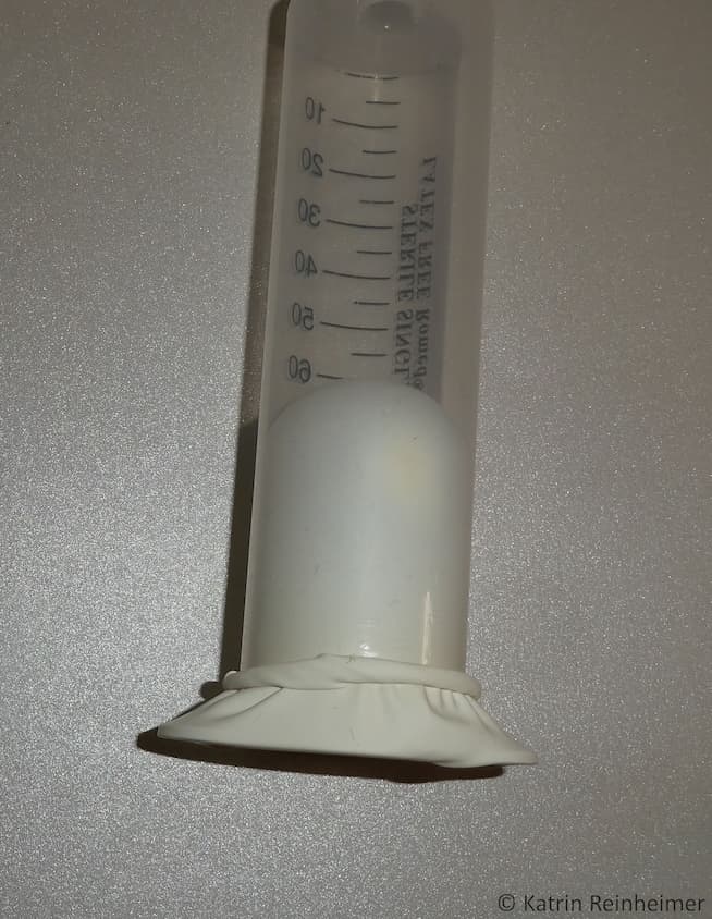 Die Gummimembran wird in die Spritze gezogen. Die Gummimembran wird in die Spritze gezogen.
