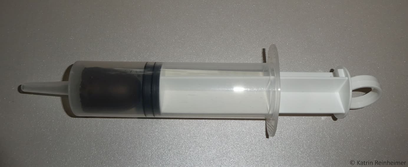 Steck den Schokokuss in die Spritze ohne ihn zu zerdrücken. Steck den Schokokuss in die Spritze ohne ihn zu zerdrücken.